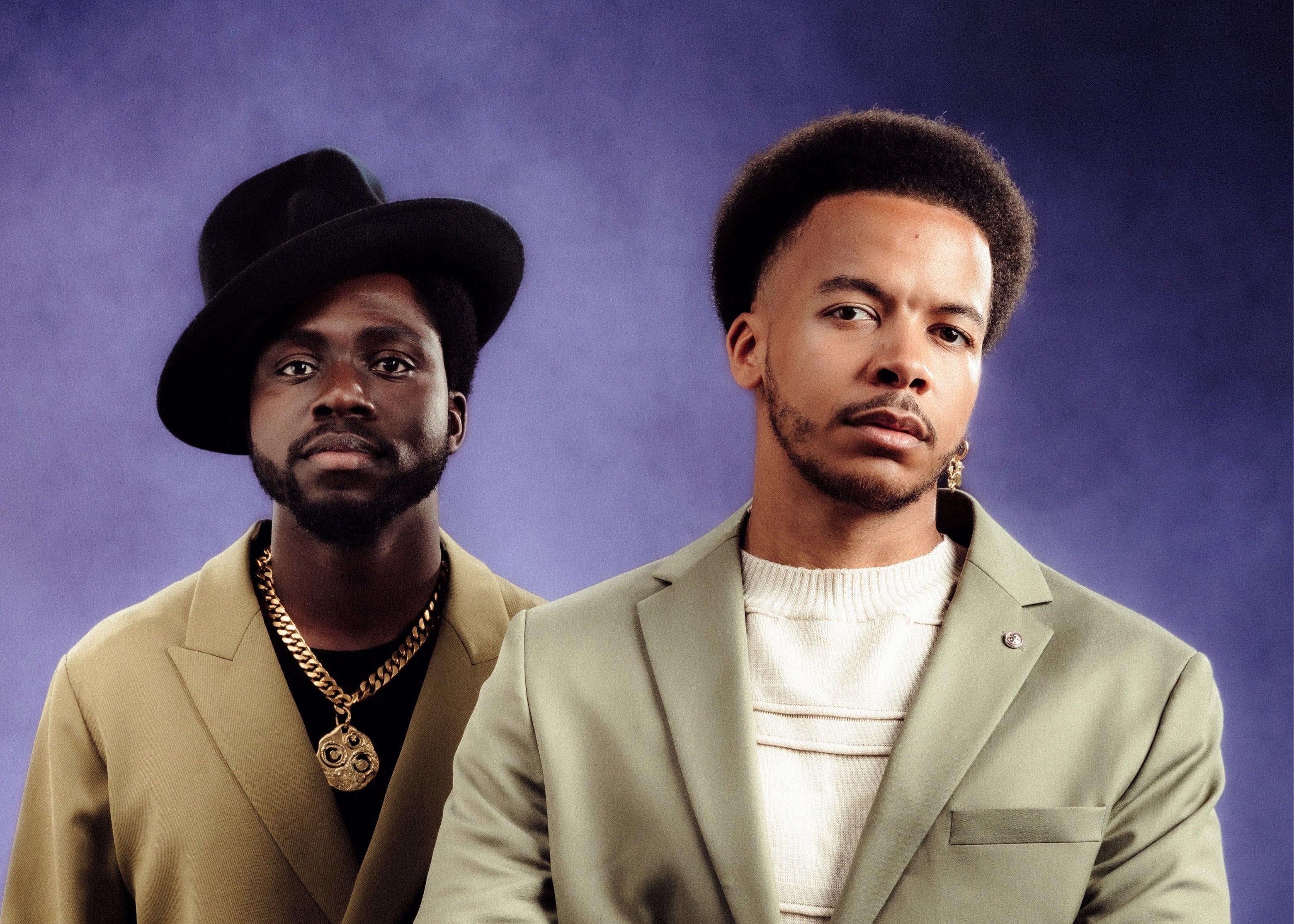 Two men in suits against a purple background